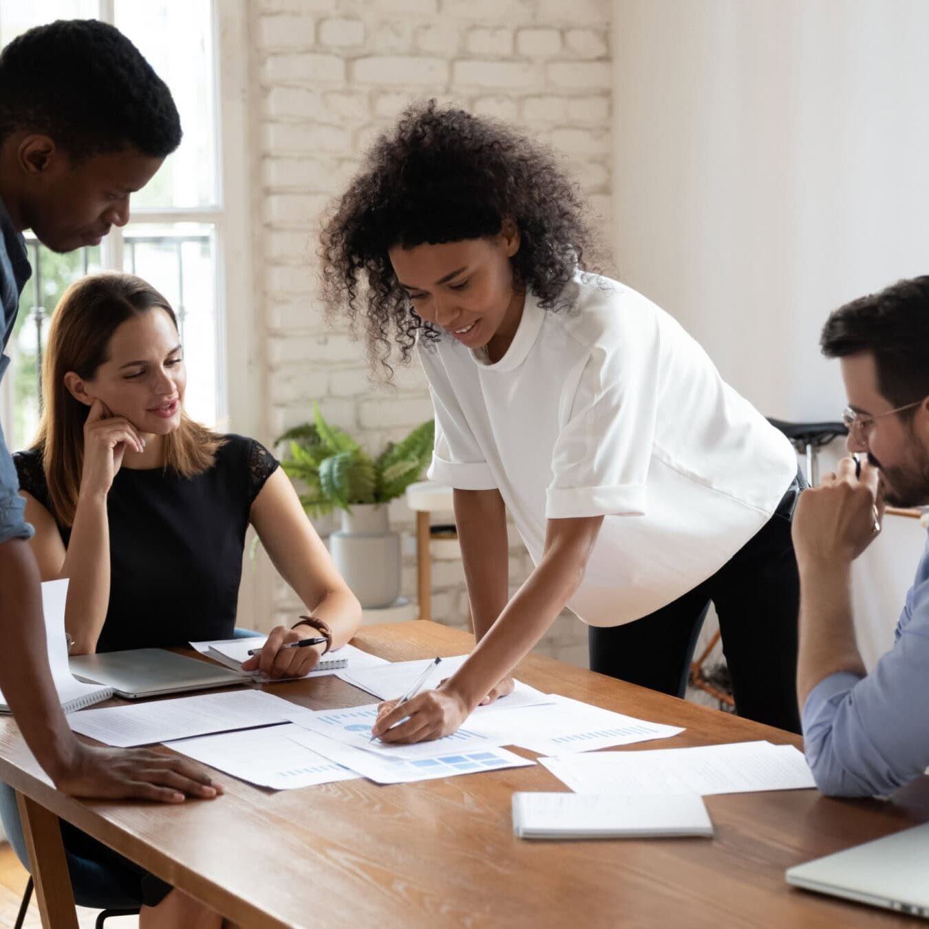 icf-about-coaching-culture-empowerment A group of professionals work together in an office reviewing several documents.