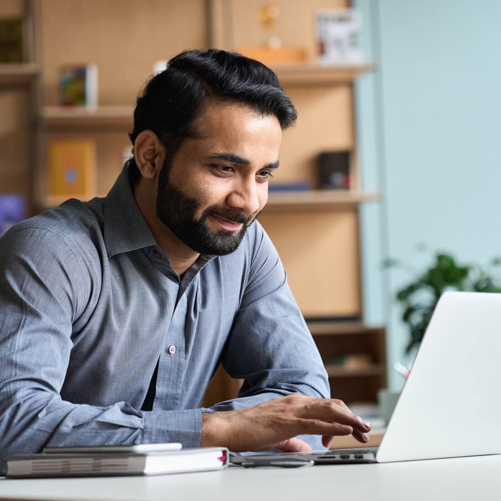 Smiling,Indian,Business,Man,Working,On,Laptop,At,Home,Office. ICF ecosystem offerings for professional and organizational development.