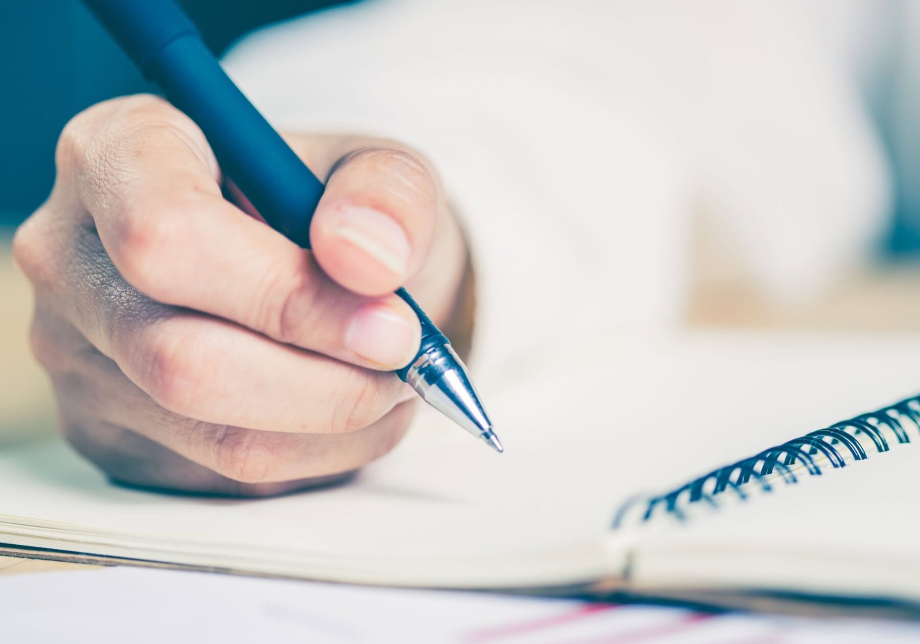 icf-academic-research-writing Someone is writing notes in a notebook on a table.