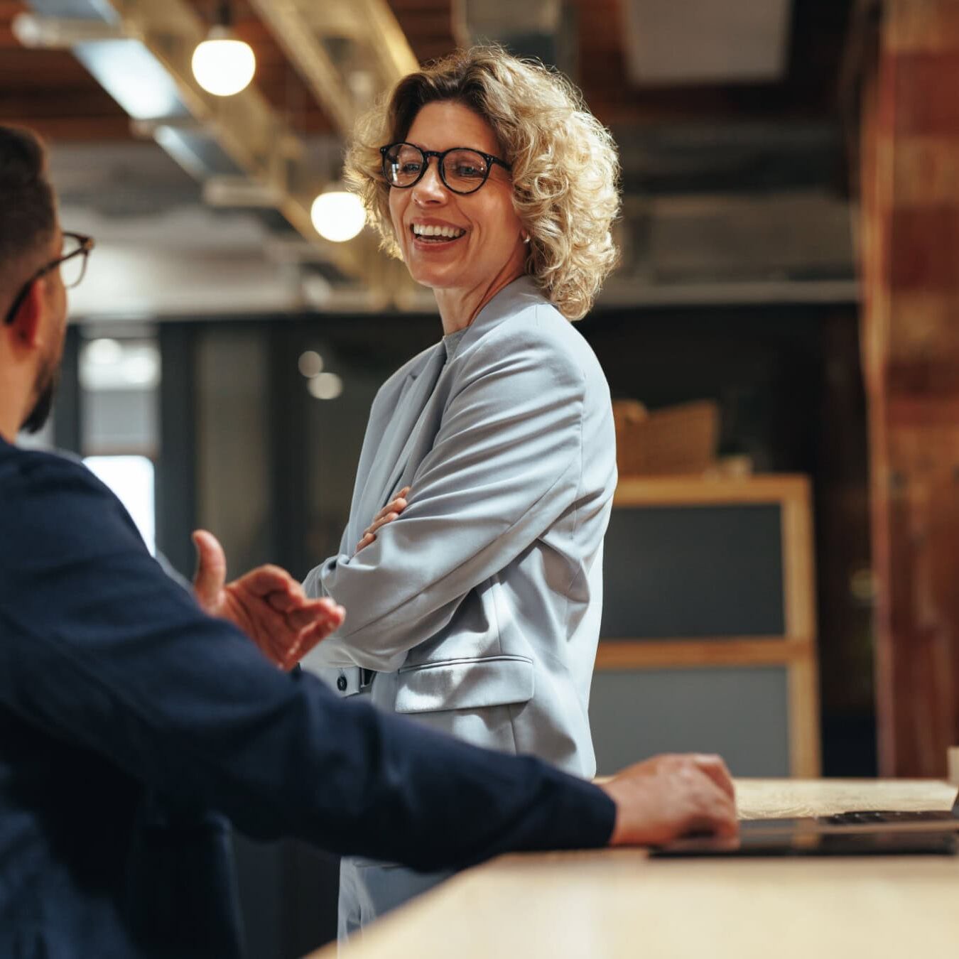 icf-credentialing-credential-requirements Woman talking to a man in an industry style office about the ICF Credential Requirements
