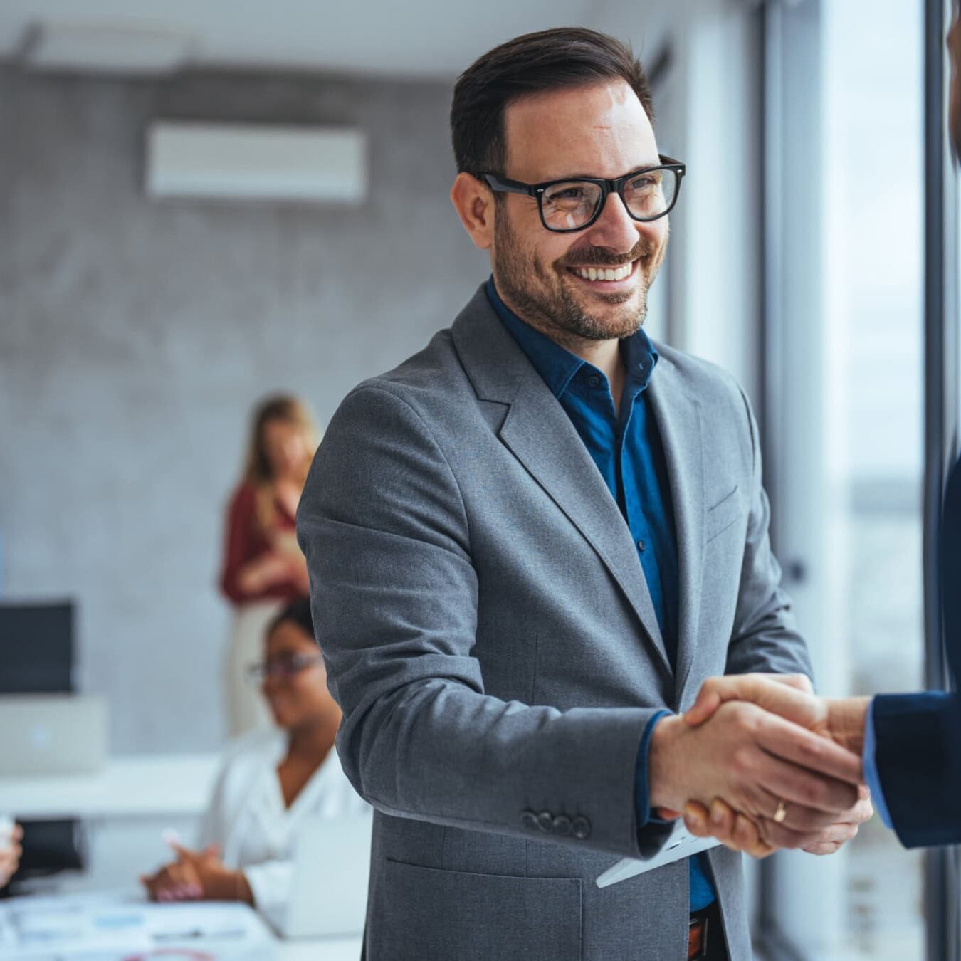 icf-credentialing-educational-requirements A man shakes hands with another man in an office after discussing the ICF credential educational requirements.